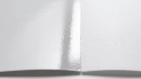 Macro close-up of glossy coated paper and matte coated paper showing differences in reflectivity and surface texture. Macro close-up of glossy coated paper and matte coated paper showing differences in reflectivity and surface texture.